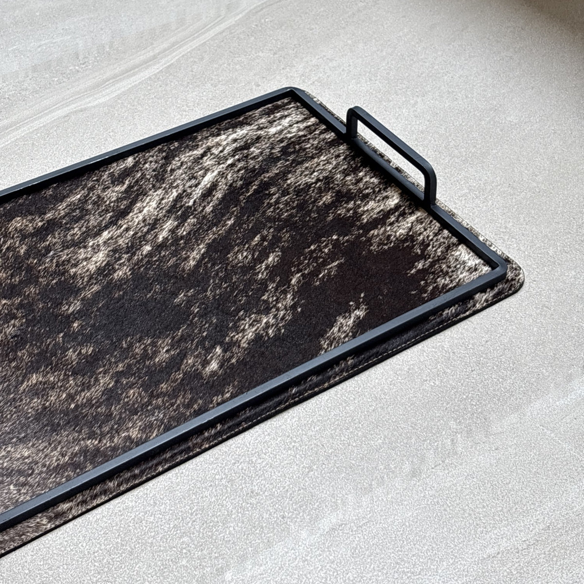 Charola cowhide grande - 323, vista cerca 2. Piel natural café y negro jaspeado y herrería negra.