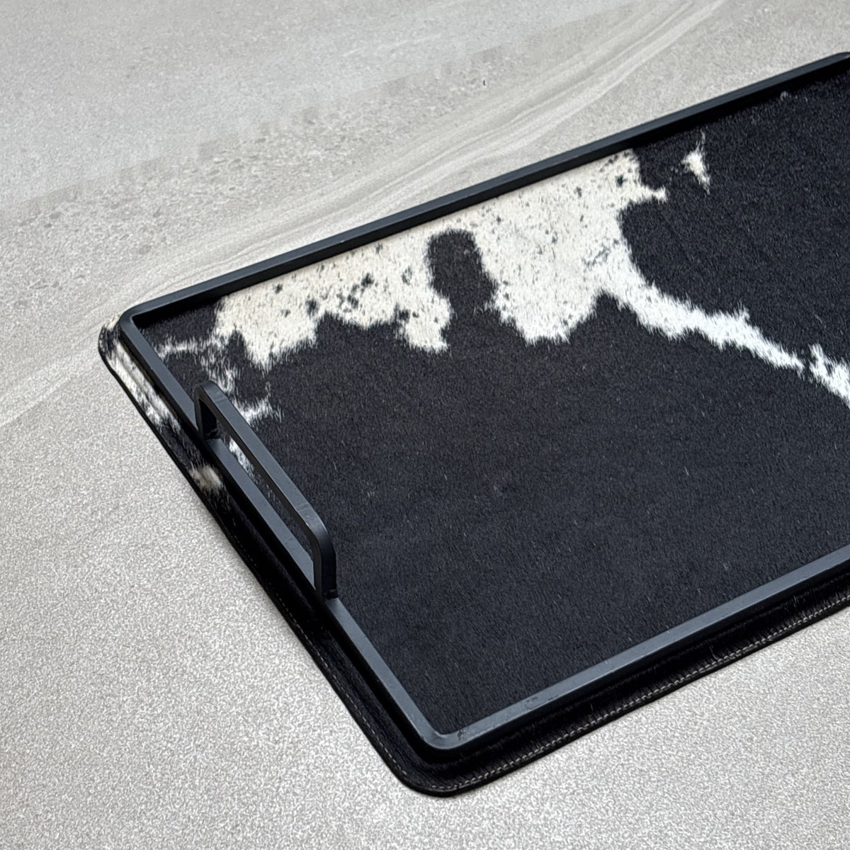 Charola cowhide grande - 328, vista cerca. Piel natural con pelo y herrería negra.