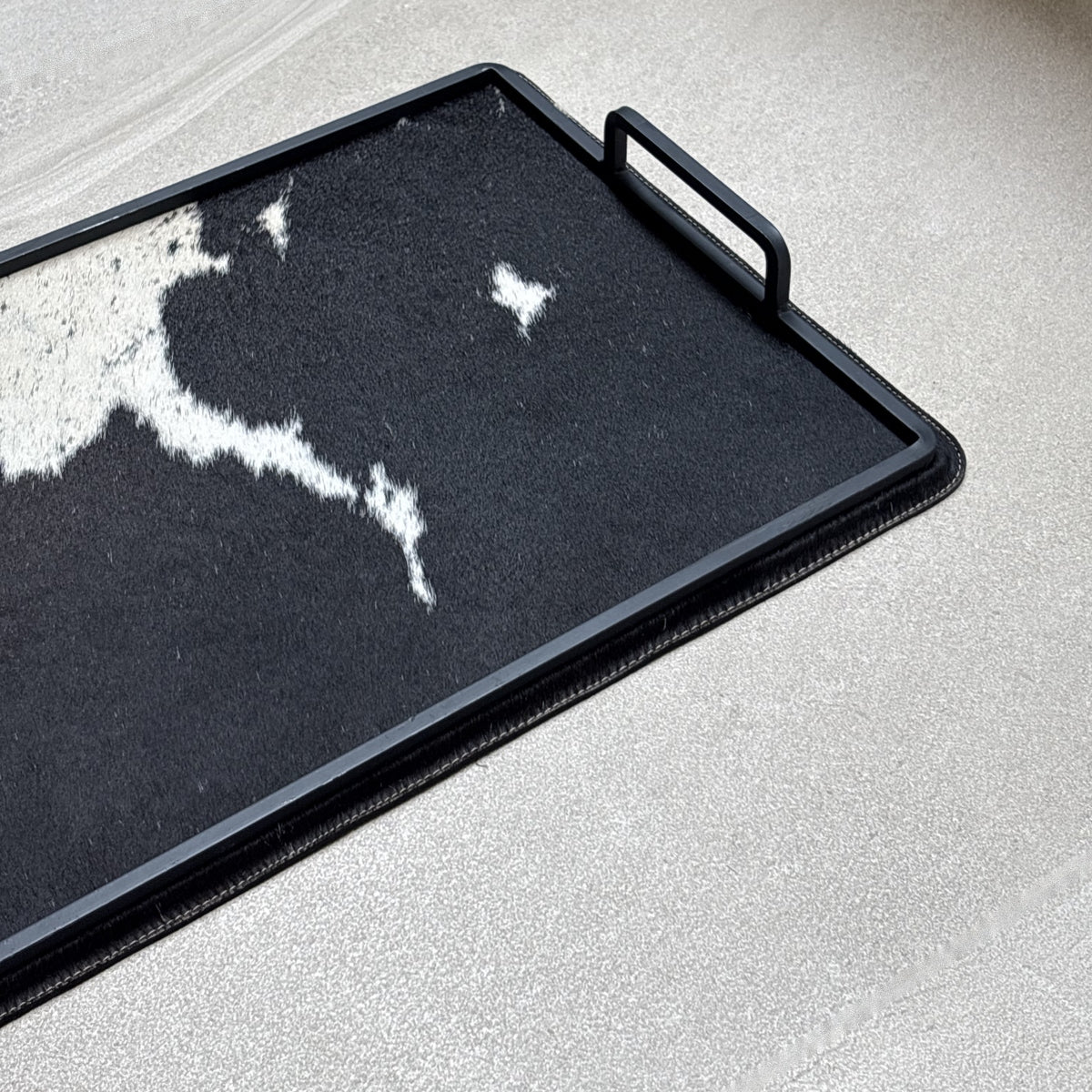 Charola cowhide grande - 328, vista cerca 2. Piel natural con pelo y herrería negra.