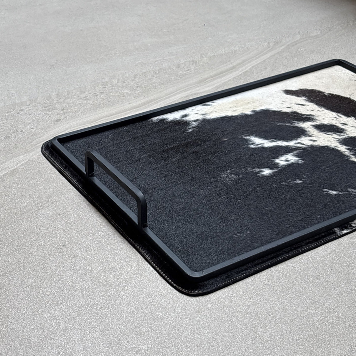 Charola cowhide grande - 328, vista cerca 3. Piel natural con pelo y herrería negra.