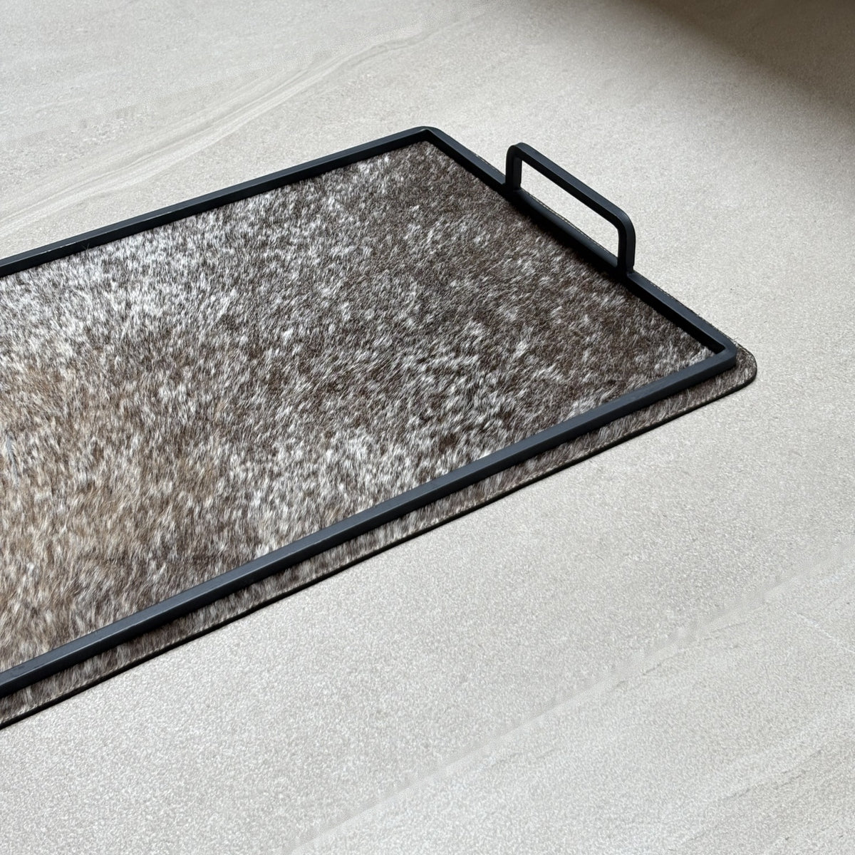 Charola cowhide grande - 331, vista cerca 2. Piel natural con pelo y herrería negra.