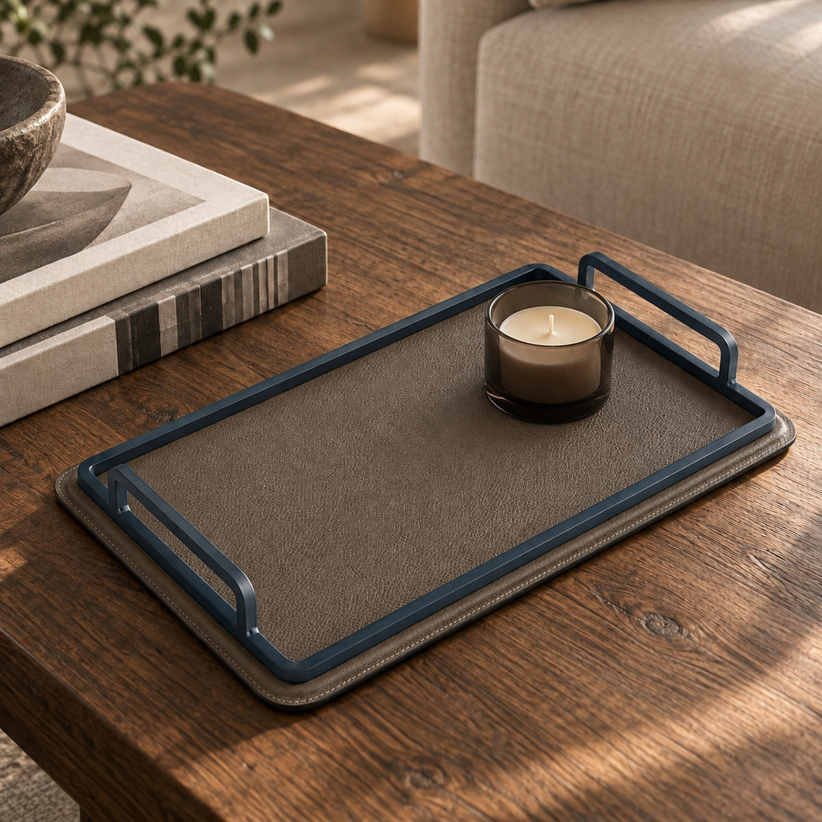 Charola greige chica de piel sobre mesa de madera con vela y libros