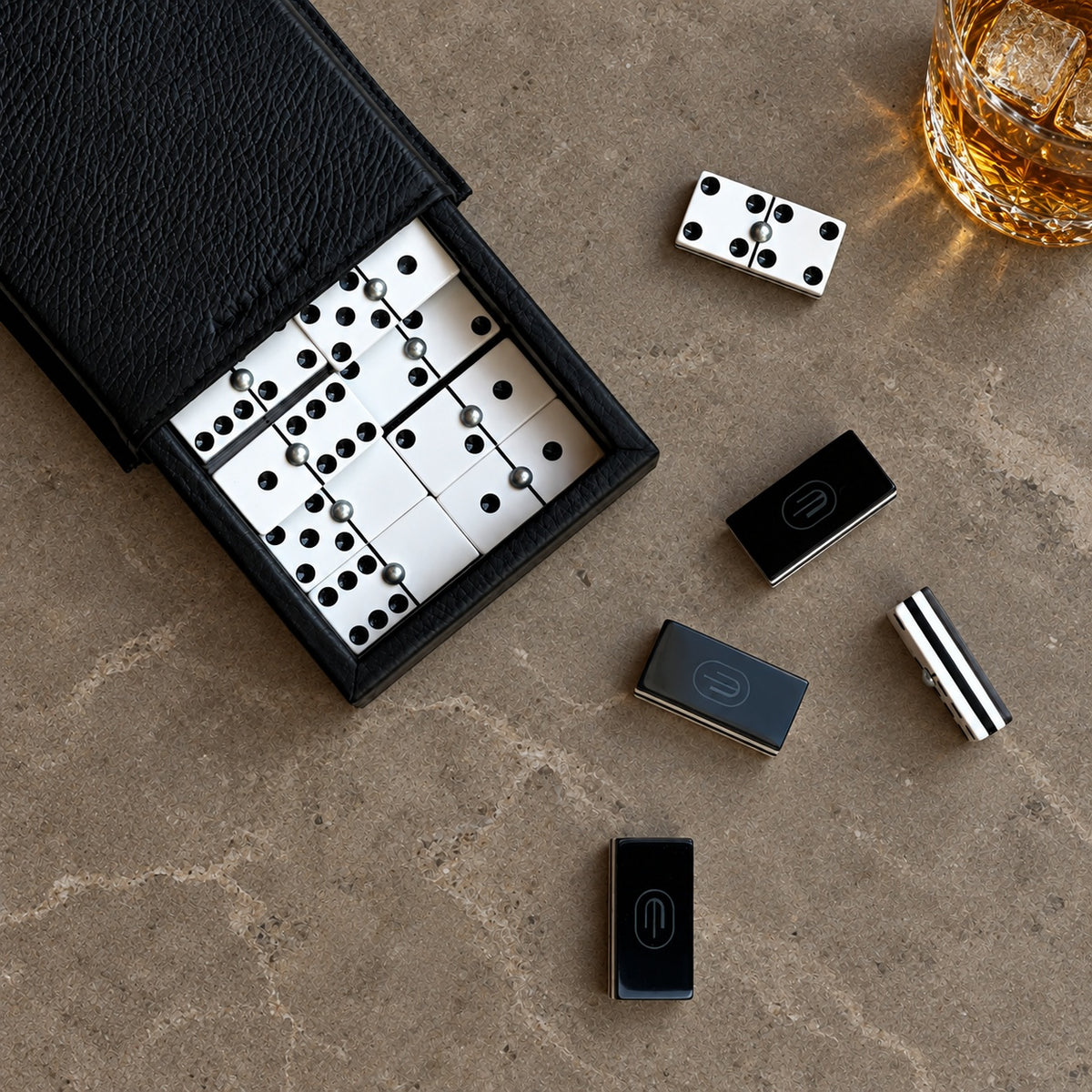 Dominó con estuche negro y whisky en las rocas