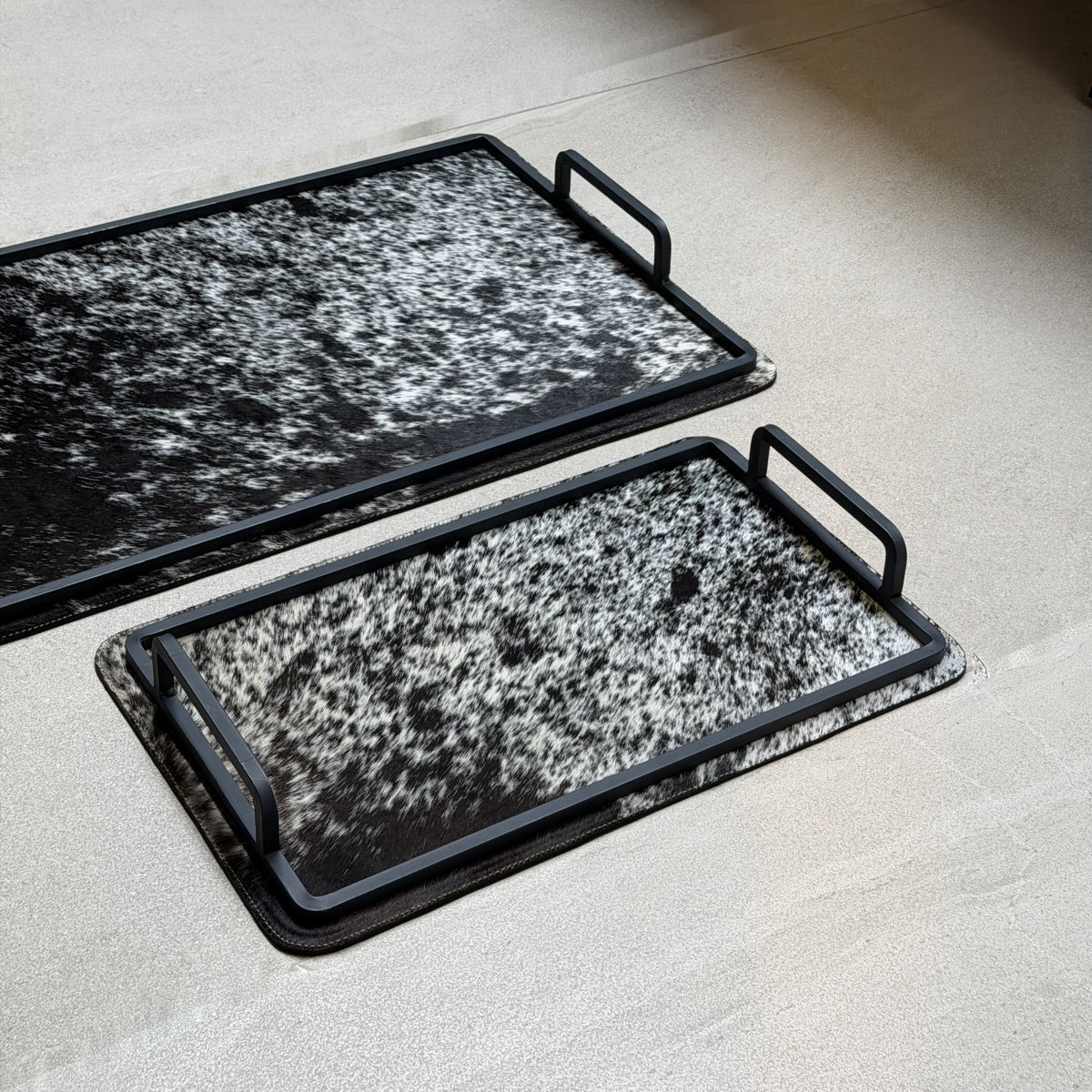 Set de charolas cowhide - 305, vista cerca 2. Piel natural negro y blanco moteado y herrería negra.