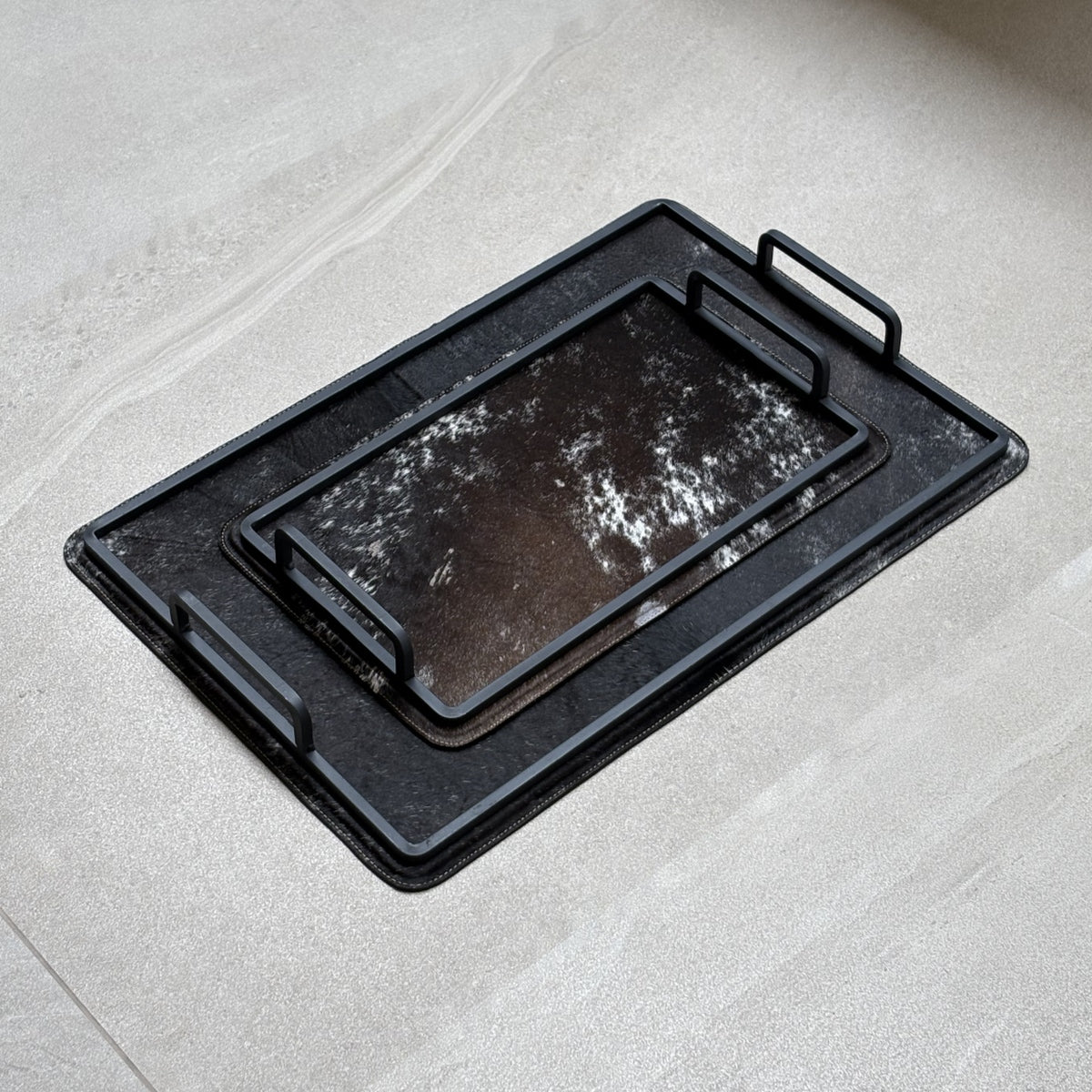 Set de charolas cowhide - 310, vista lejos 2. Piel natural negro y café con blanco y herrería negra.