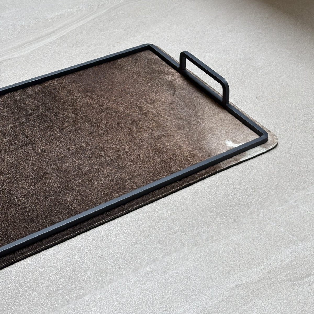 Charola cowhide grande - 333, vista cerca. Piel natural con pelo y herrería negra.