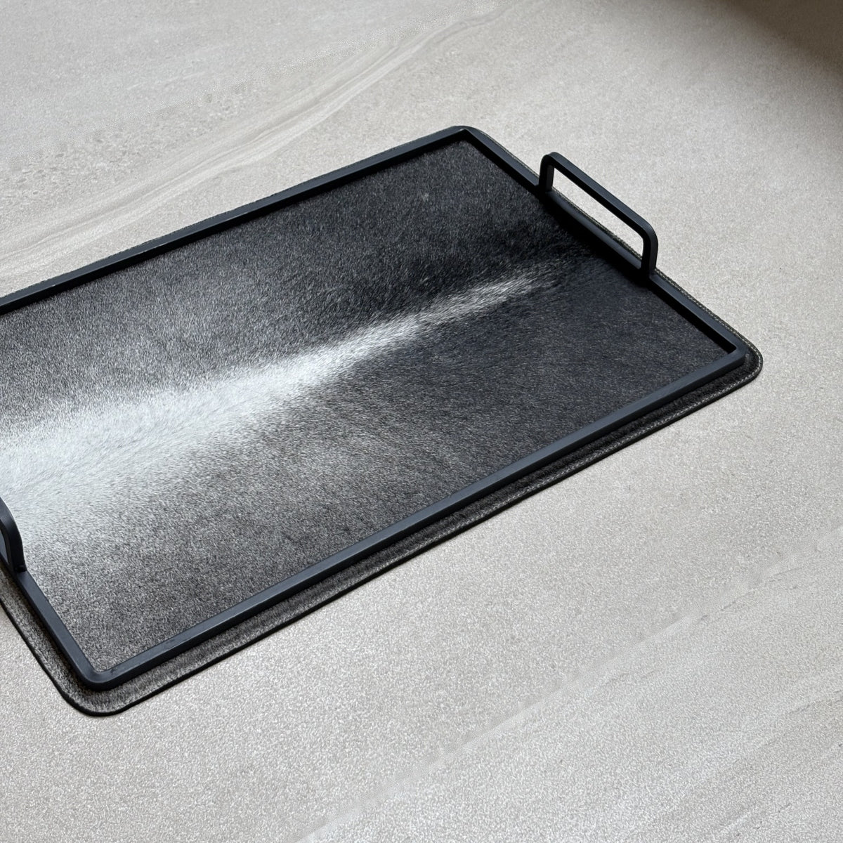 Charola cowhide grande - 334, vista cerca 2. Piel natural con pelo y herrería negra.