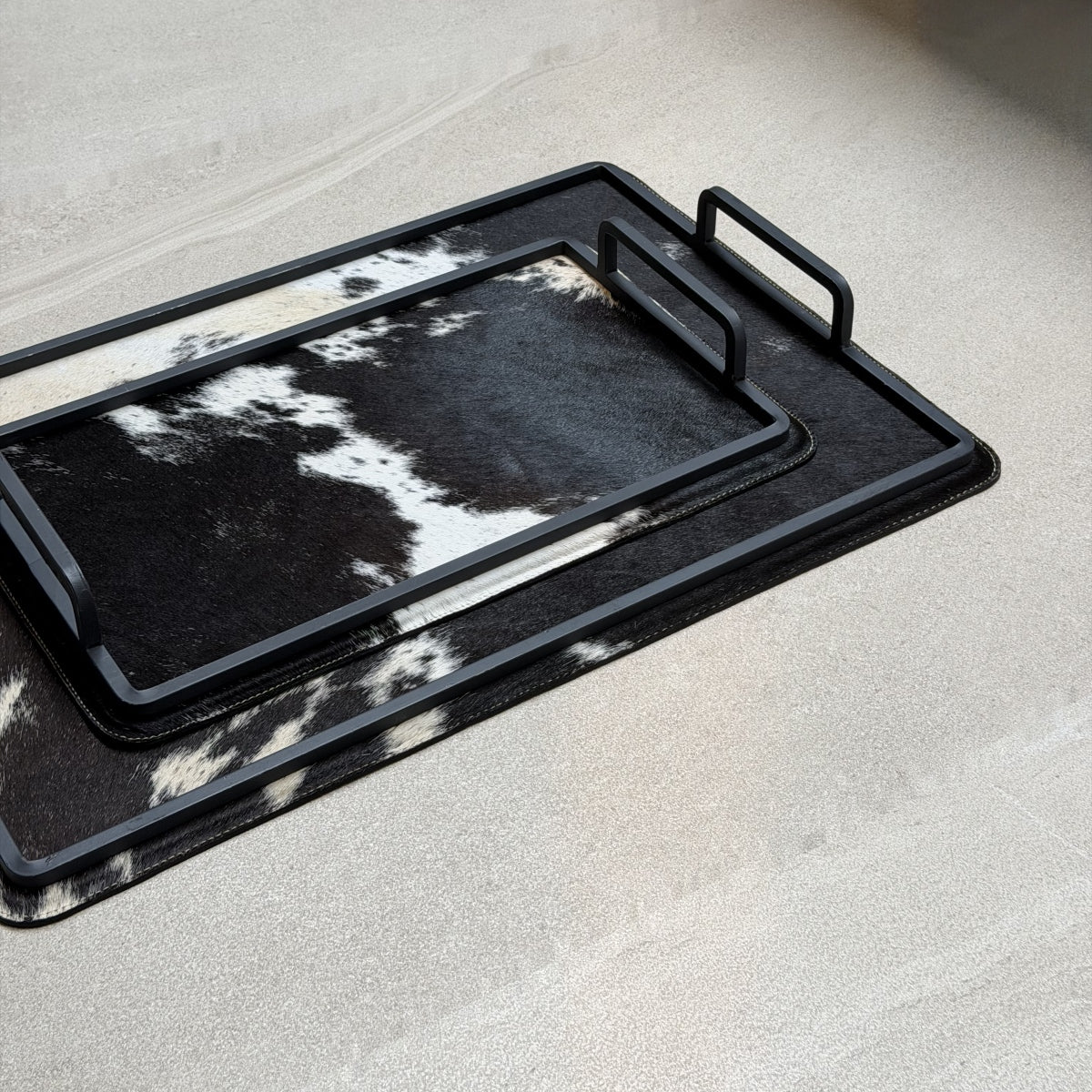 Set de charolas cowhide - 296, vista cerca. Piel natural negro y blanco y herrería negra.