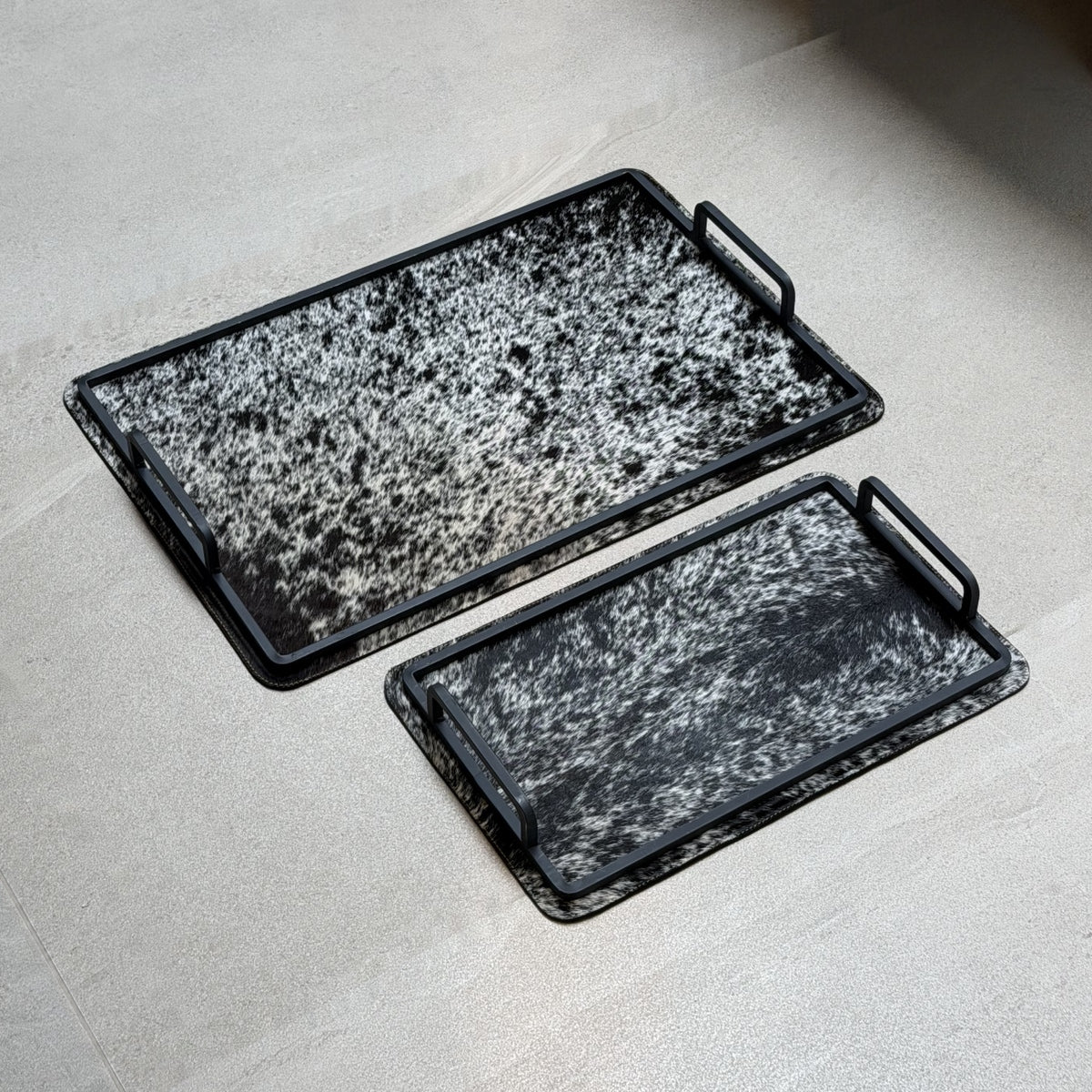 Set de charolas cowhide - 297, vista lejos 2. Piel natural negro y blanco moteado y herrería negra.