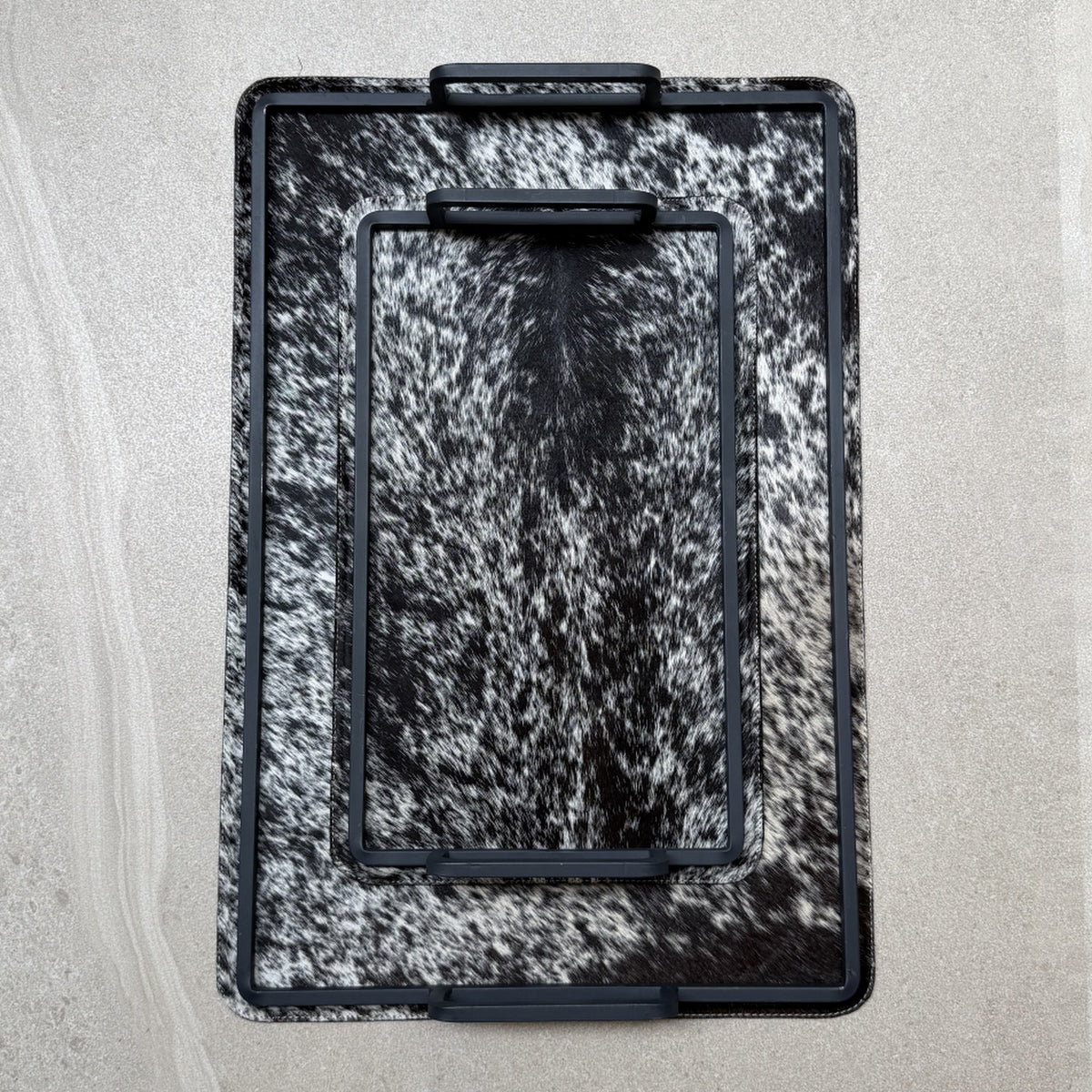 Set de charolas cowhide - 297, vista superior. Piel natural negro y blanco moteado y herrería negra.