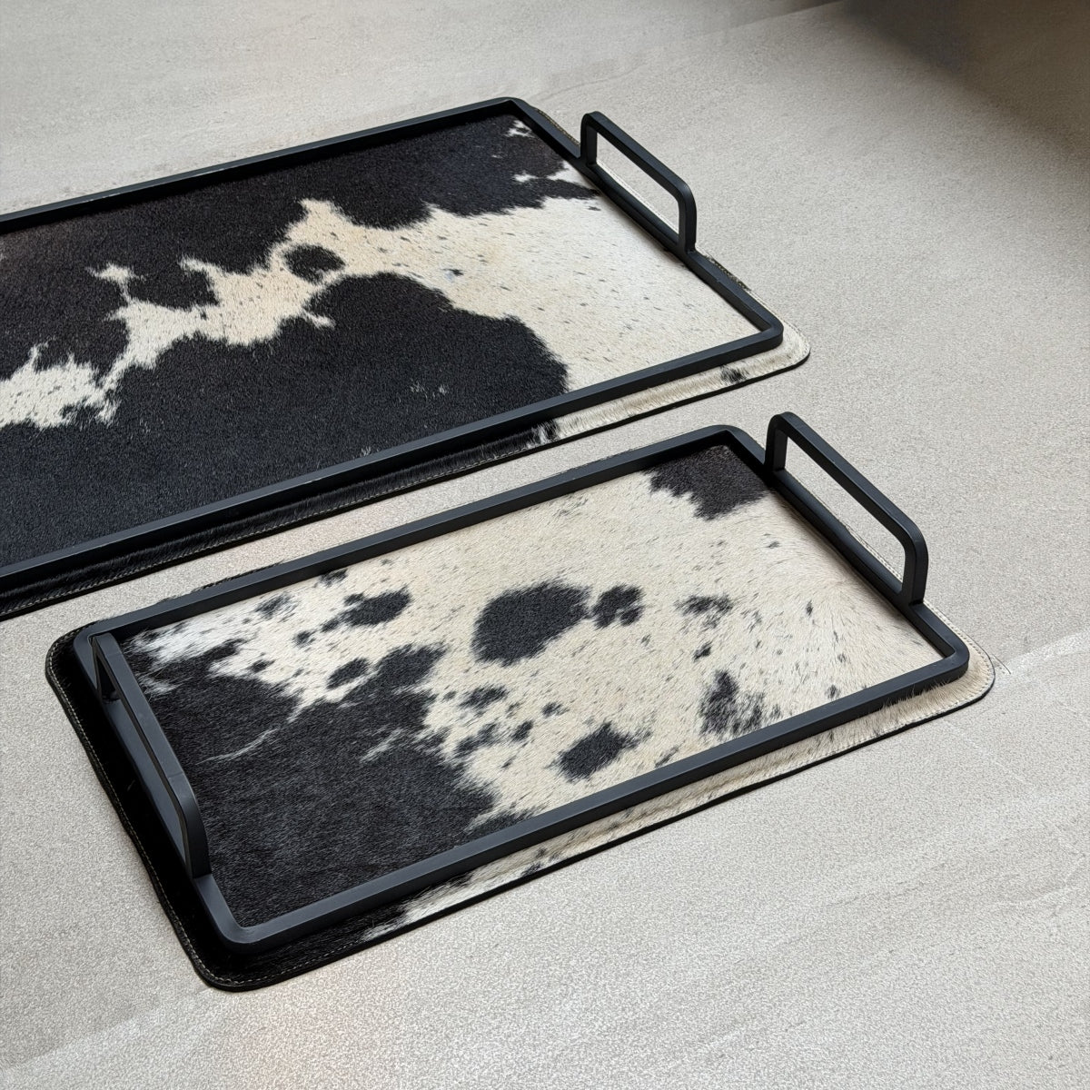Set de charolas cowhide - 298, vista cerca 2. Piel natural blanco y negro y herrería negra.