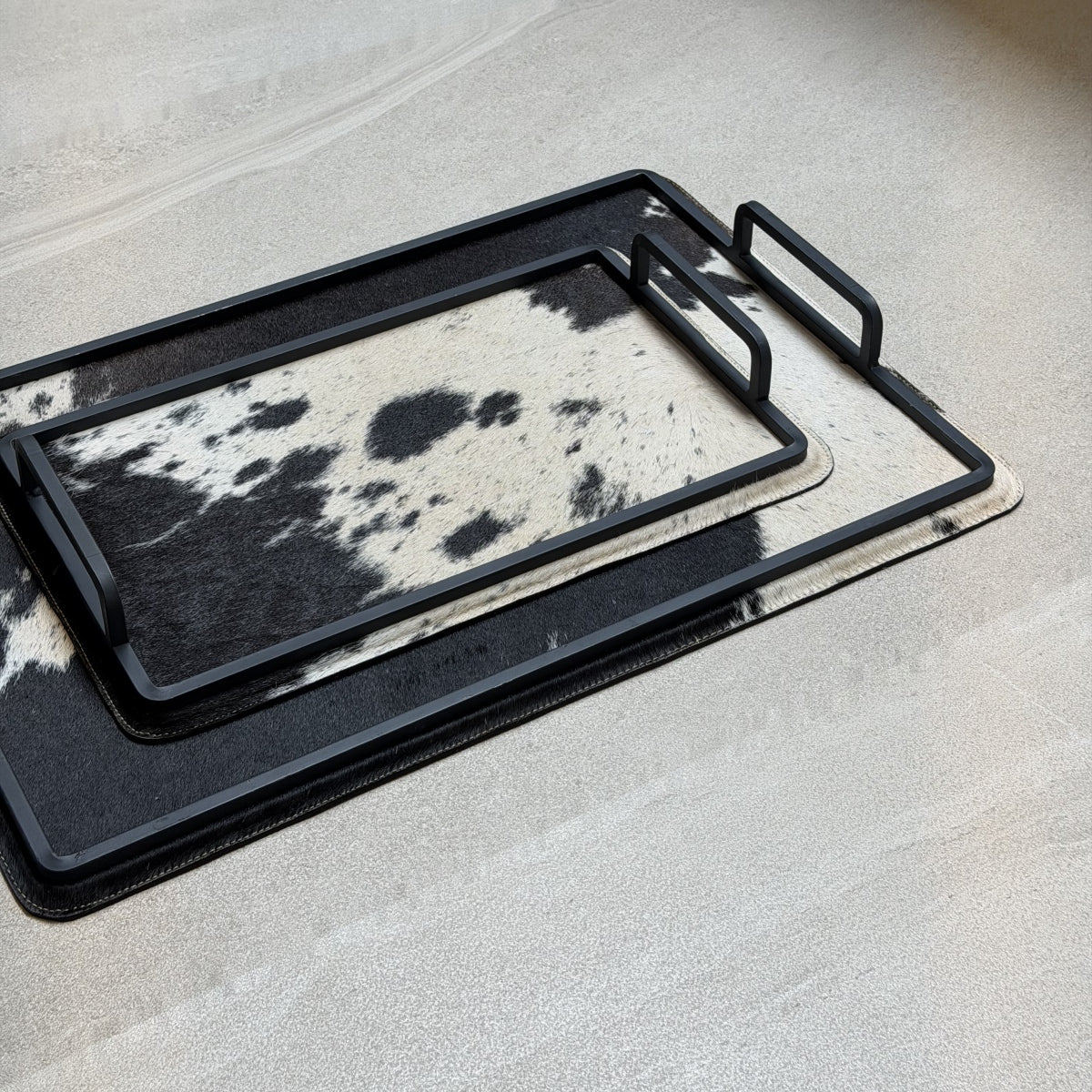 Set de charolas cowhide - 298, vista cerca. Piel natural blanco y negro y herrería negra.