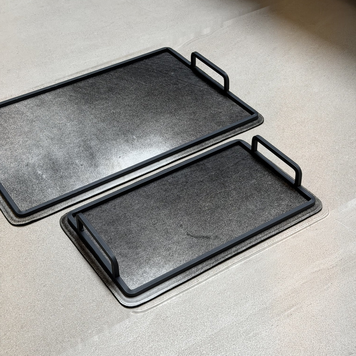 Set de charolas cowhide - 302, vista cerca 2. Piel natural gris oscuro y herrería negra.