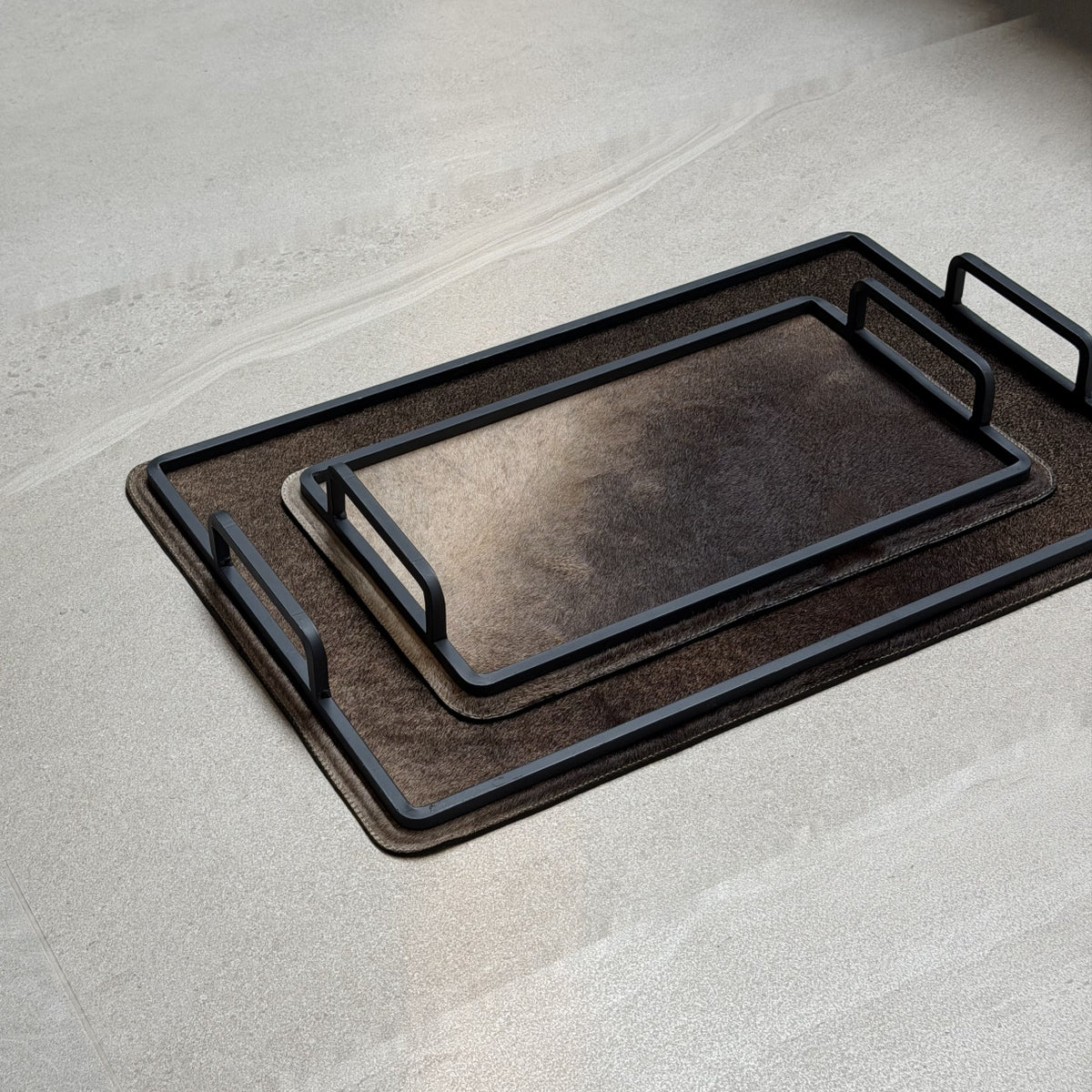 Set de charolas cowhide - 303, vista cerca. Piel natural café con matices claros y herrería negra.