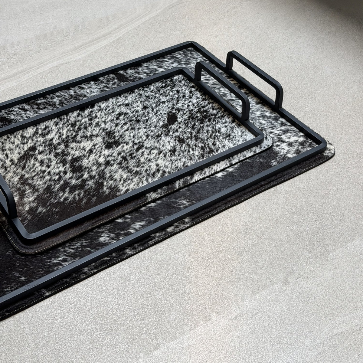Set de charolas cowhide - 305, vista cerca. Piel natural negro y blanco moteado y herrería negra.